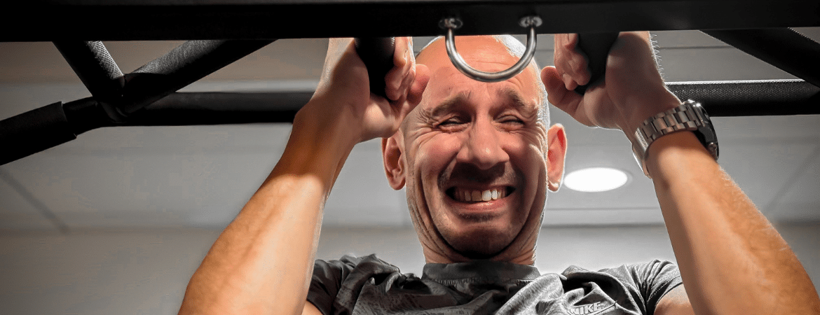 Un homme fait une traction sur une machine de musculation.