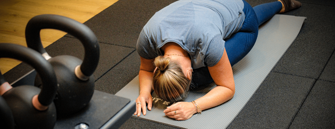 Une femme faisant ses étirements sur un tapis de fitness.